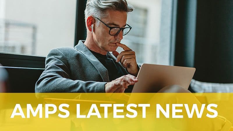 A man in glasses working on a laptop, above the words AMPS Latest News